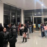 Students and visitors attending an art exhibition on campus, viewing artworks and interacting in the gallery space.