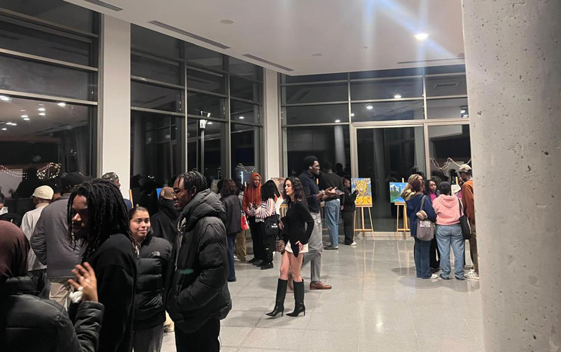 Students and visitors attending an art exhibition on campus, viewing artworks and interacting in the gallery space.
