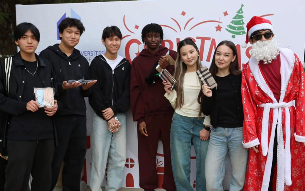 Students posing together at a Christmas event on campus, holding gifts and standing next to a person dressed as Santa Claus.
